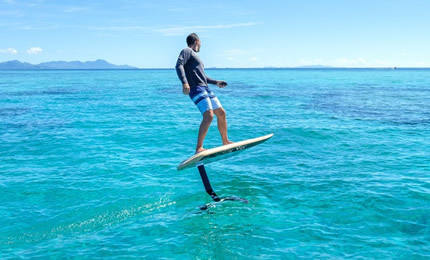 Man riding an electric hydrofoil in the ocean. 